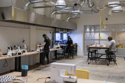 People using tools and machines in the Makerspace at the LPCPL Exchange.