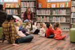 Children and parents sit on the floor at the Library during Storytime. 